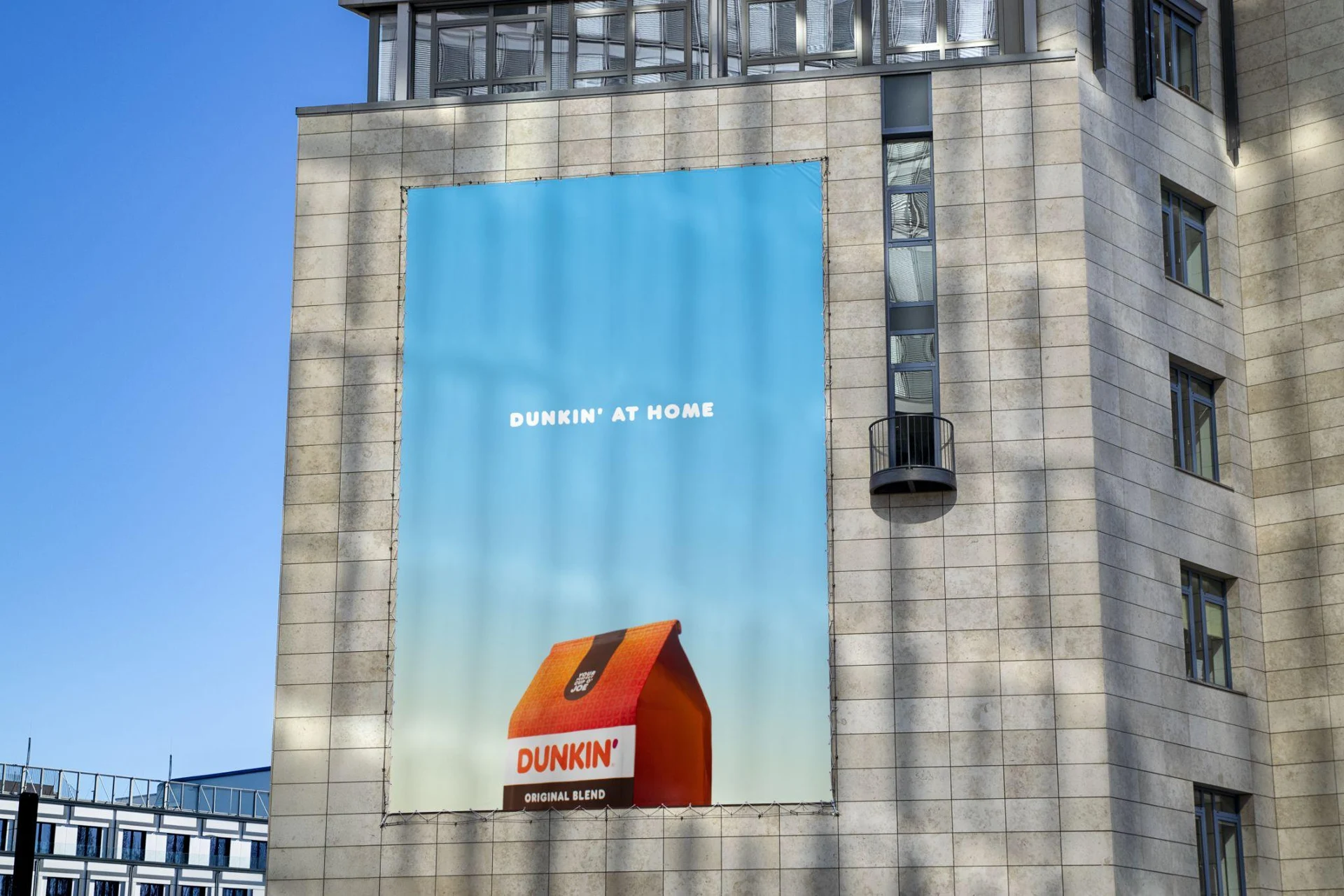 Dunkin' at Home campaign displayed on a building facade